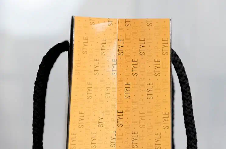 Schwarze Orange Papiertragetasche mit Stoffkordeln auf weißen Hintergrund